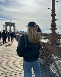 a woman standing on a bridge looking at the water