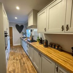 a kitchen with white cabinets and wooden counter tops, along with hardwood flooring in the middle