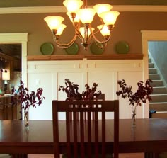 a dining room table and chairs with vases on top of them, in front of a doorway