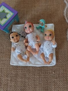 three baby dolls laying on top of a blanket