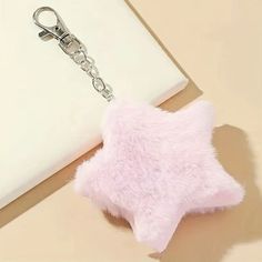 a pink star shaped keychain sitting on top of a white table next to a laptop