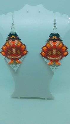 a pair of earrings that are made out of bead and plastic beads with an orange fish on it