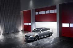 a silver car parked in front of a red wall