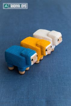 three small knitted sheep sitting on top of a blue surface