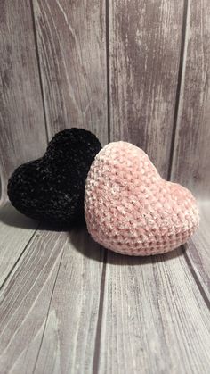 two black and pink hearts sitting on top of a wooden table next to each other