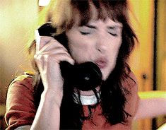 a woman talking on a cell phone while sitting at a table