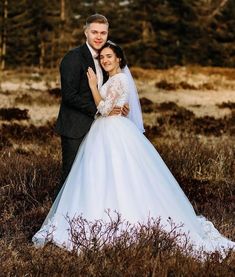 a bride and groom pose for a wedding photo in the middle of an open field