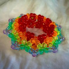 a rainbow colored bracelet made out of plastic beads on a white sheet with a flower design