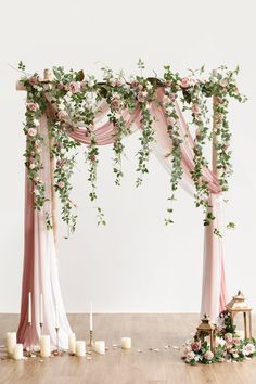 a wedding arch decorated with pink and white flowers, greenery and candles on the floor