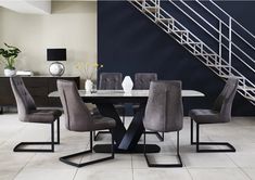 a dining room table and chairs with grey upholstered chairs in front of a stair case