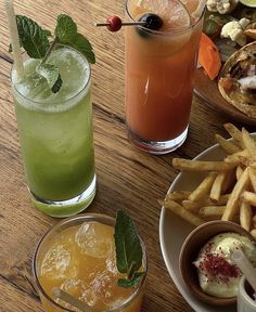 three different types of drinks are on the table next to plates with food and drink glasses