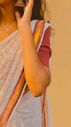 a woman in a sari talking on her cell phone while holding a small bell