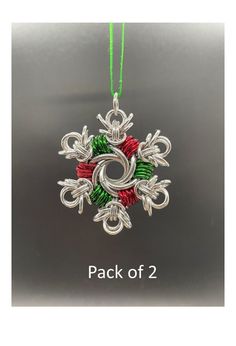 a christmas ornament hanging from a green string on a gray background with snowflakes