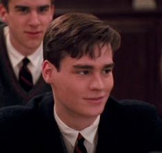 two young men in suits and ties looking at the camera