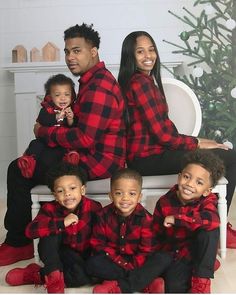 a family wearing matching red and black flannel outfits sitting on a white bench