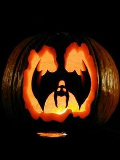 a carved pumpkin with an image of a bat on it's face in the dark