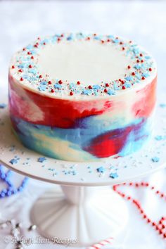 a red, white and blue cake with sprinkles on it sitting on a plate