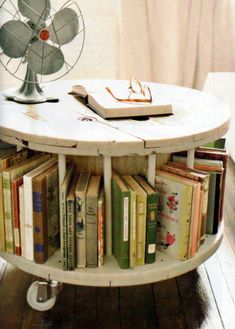 a round table with books on it in front of a fan