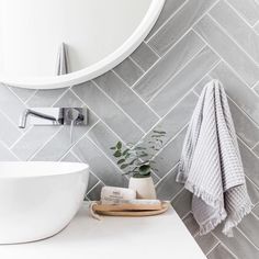 a white sink sitting under a bathroom mirror next to a wooden tray filled with towels