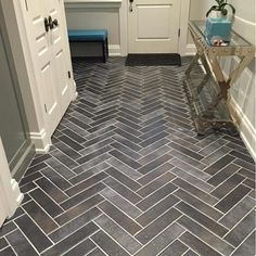 a bathroom with gray herringbone tile flooring and white trim on the door way