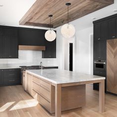 a large kitchen with black cabinets and white counter tops, an island in the middle