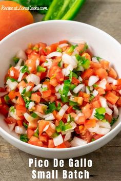 a white bowl filled with salsa next to some tortilla chips and a lime