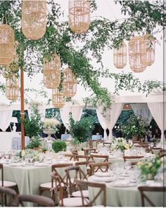 tables and chairs are set up for an outdoor wedding reception with chandeliers hanging from the ceiling