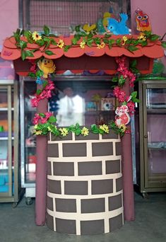 a fake brick wall with flowers and vines on it in front of a display case