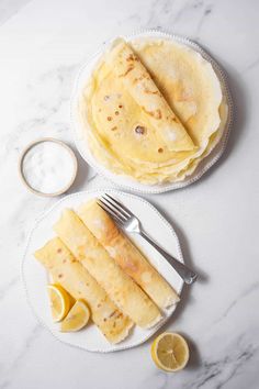 two plates with pancakes and lemon slices on them