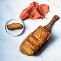 a loaf of pumpkin bread on a wooden cutting board next to a bowl of powdered sugar