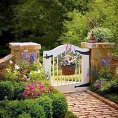 a white gate surrounded by flowers and greenery