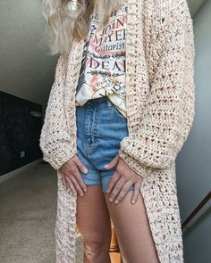 a woman standing in front of a mirror wearing shorts and a cardigan sweater with her hands on her hips