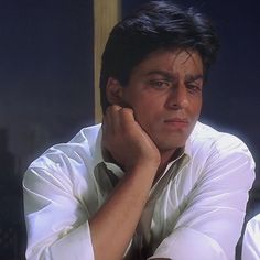 a man sitting at a table with his hand on his chin and looking off to the side