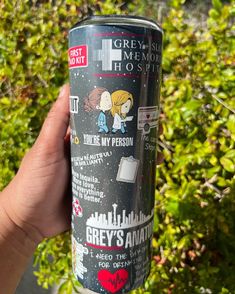 a person holding up a can of grey's anatomy hot sauce in front of some bushes