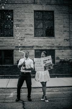 a man and woman holding signs in front of a building with bubbles coming out of them