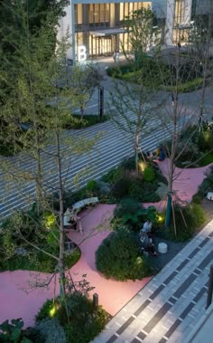 an aerial view of a building with trees and bushes in the foreground, at night