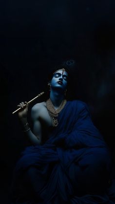 a woman with blue makeup holding a stick