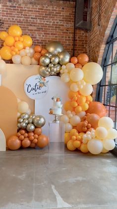 an assortment of balloons are on display in front of a brick wall and arched window