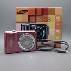 a pink digital camera sitting next to a box with an e528 logo on it