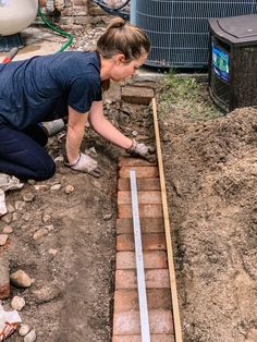 a woman is laying bricks in the ground