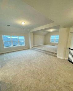 an empty living room with carpet and windows