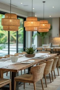 a dining room table with chairs and lights hanging from it's ceiling, next to a large window