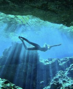 a woman is swimming in the water near some rocks and algae growing on the ground