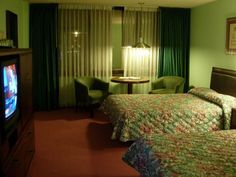 a hotel room with two beds and a television in the corner next to each other