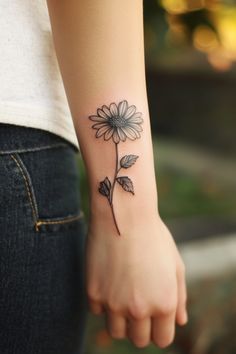 Person with a black and white flower tattoo on their forearm. Daisy Tattoos For Women, Anklet Tattoos