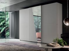 a living room with an open sliding door and plants on the table in front of it