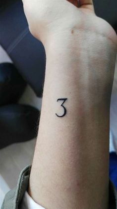 a woman's wrist with the number three tattooed on her left arm, in black ink