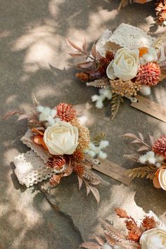 three wedding bouquets with flowers and leaves on the ground in front of some trees