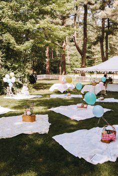 an outdoor party with balloons and picnic tables