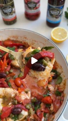 a spoon full of chicken and vegetables being lifted from a bowl with lemons in the background